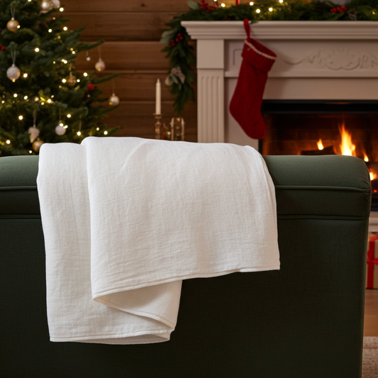Linen quilt on a green velvet sofa with lit fireplace in the background