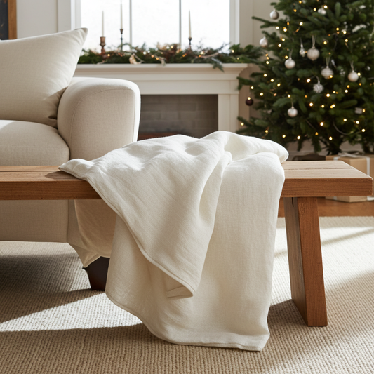 The image of a linen quilt on a wooden bench with a christmas tree in the background