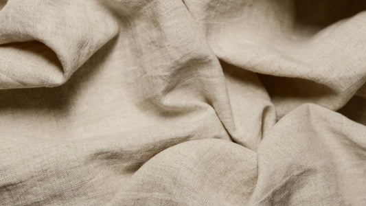 Close-up of undyed linen fabric softly crumpled together, revealing its natural texture