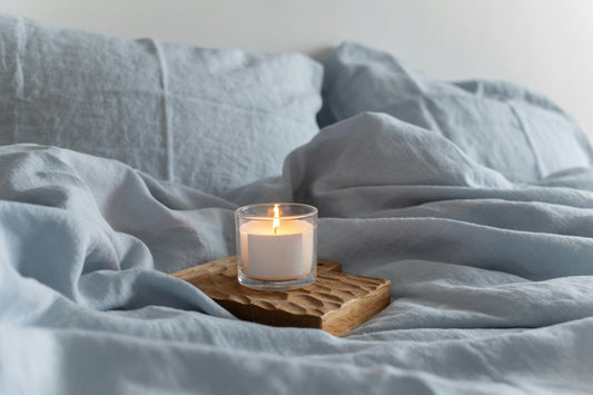 An image of a candle on linen sheets