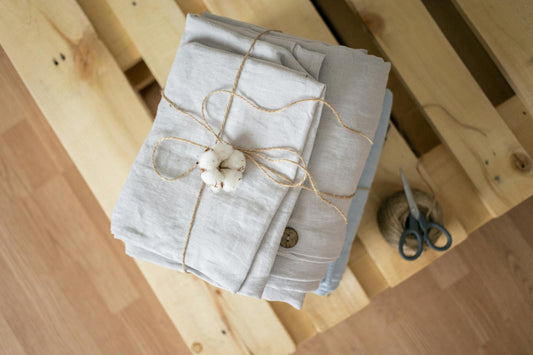 Soft linen fabric neatly folded and tied with a bow, showcasing its texture and natural drape