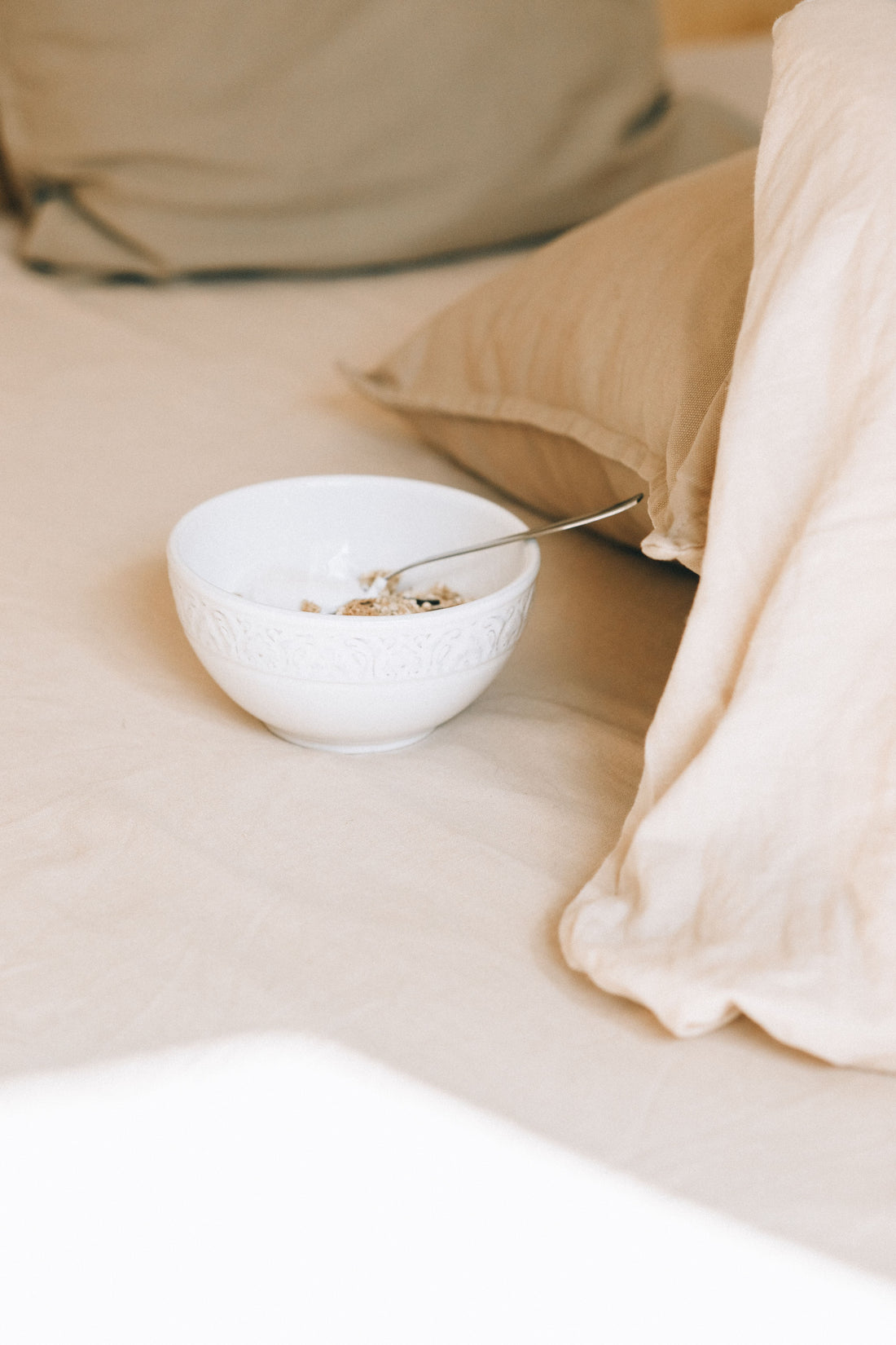 cereal bowl on a bed covered in linen