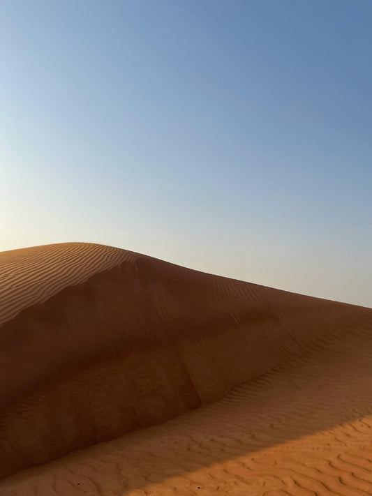 Desert dunes under a cloudless sky—evoking heat and dryness, a stark contrast to the cooling relief of linen quilts.