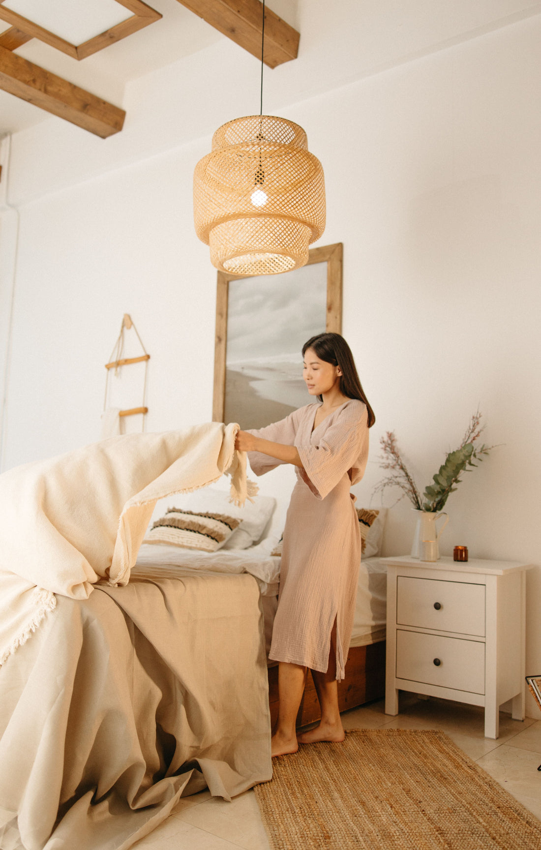 Interior designer styling a bed with linen bedding in an organic modern bedroom featuring natural textures, earthy tones, and minimalist decor.