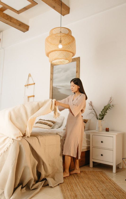 Interior designer styling a bed with linen bedding in an organic modern bedroom featuring natural textures, earthy tones, and minimalist decor.