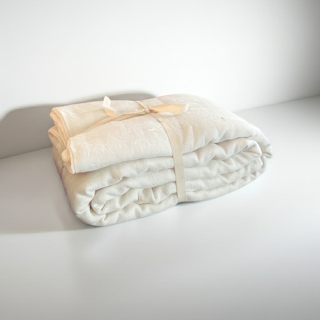 Folded beige blanket or linen quilt on a white surface