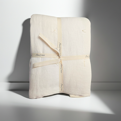 Folded beige linen quilt with a ribbon on a white background