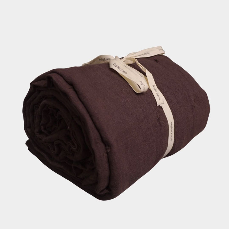 Chocolate brown linen quilt with hand-tied quilting details, rolled and tied with ribbon.